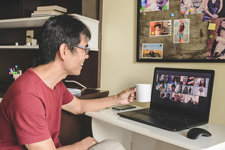Photo of man drinking coffee during a Zoom meeting