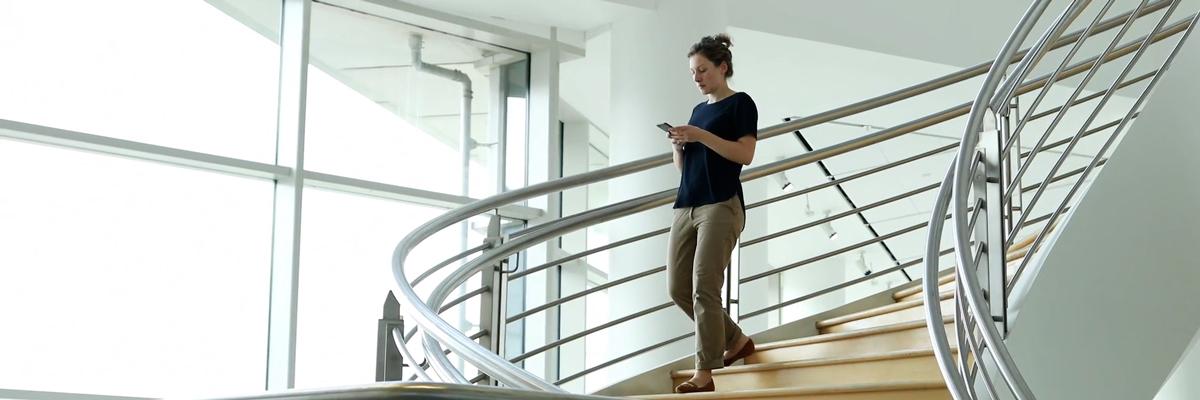 a woman walking down a spiral staircase and looking at her mobile phone